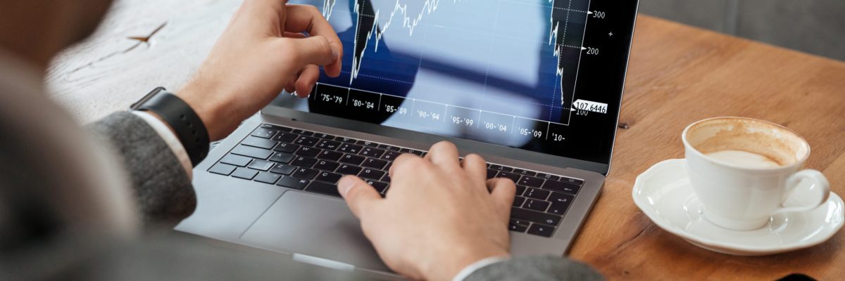Cropped image of business man sitting by the table in cafe and analyzing indicators on laptop computer